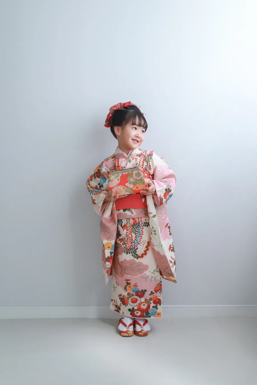 白い壁の前に立つ着物姿の女の子
