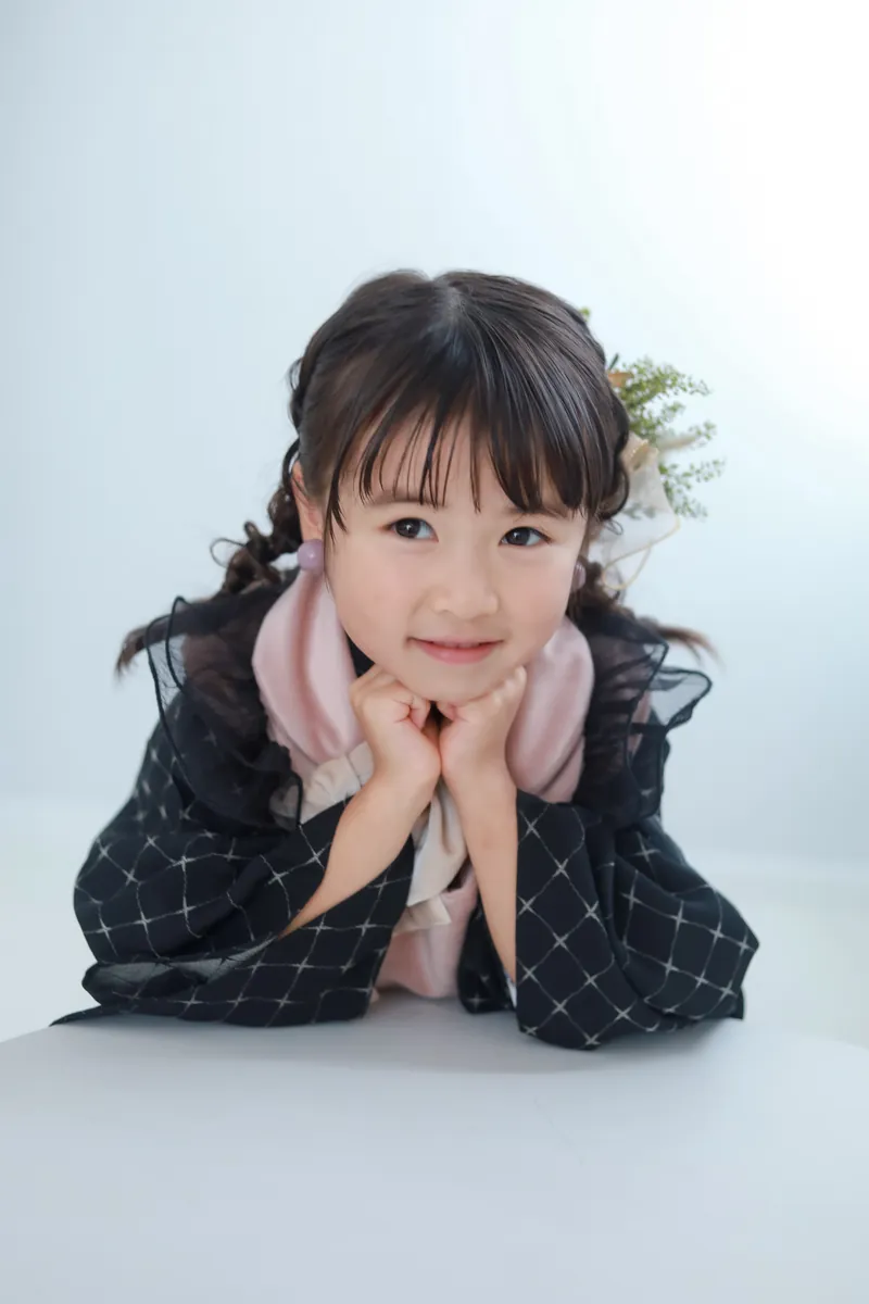 顎の下で手を合わせて笑う被布姿の女の子