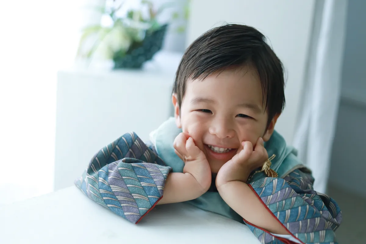 頬づえをついて笑う着物姿の男の子