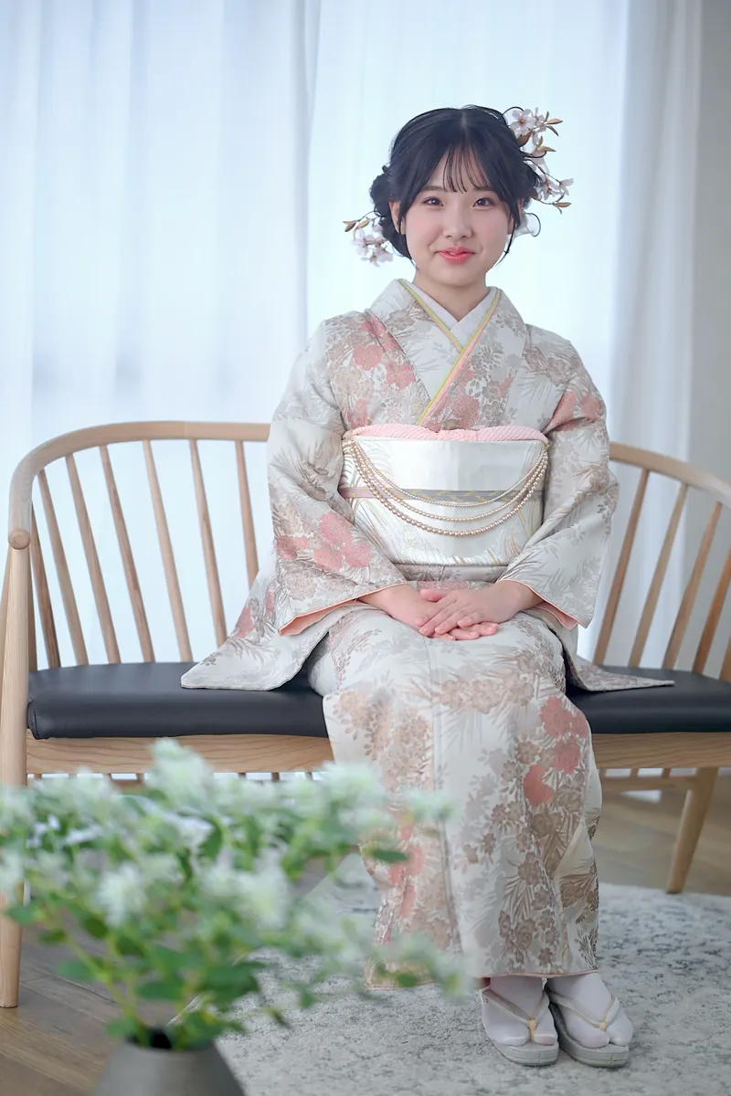 椅子に腰かける訪問着姿の女性